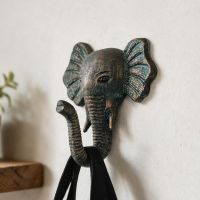 A Close up of the Verdigris Elephant Hook on a Sand Coloured Wall next to a Shelf - Digital Illustration 