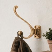 A Close up view of the Brass Hat and Coat Hook with Square Back Plate on a White Wall next to a Plant - Digital Illustration 