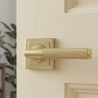 A Close up View of the Satin Brass "Royale" Square Concealed Door Handle on Rose Set on a Classic Cream Coloured Door in a Modern Home - Digital Illustration 