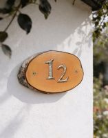 A Number 12 Natural Hard Wood Rustic House Number Sign Mounted on a Sunny Cottage Wall - Digital Illustration