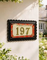 A Number 197 "Scarlett Garden" Large Black Iron & Ceramic House Sign Mounted on a White Coloured Cottage Wall - Digital Illustration