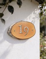 A Number 19 Natural Hard Wood Rustic House Number Sign Mounted on a White Garden Cottage Wall - Digital Illustration 