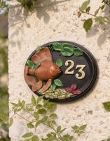 A Number 23 "Wellhurst Lakes" Hand Painted Goldfish House Sign Mounted on a sunny Cottage Garden Wall - Digital Illustration
