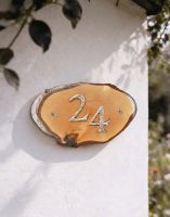 A Number 24 Natural Hard Wood Rustic House Number Sign Mounted on a Sunny White Garden Wall - Digital Illustration
