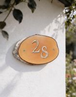 A Number 28 Natural Hard Wood Rustic House Number Sign Mounted on a Cream Coloured Cottage Wall - Digital Illustration