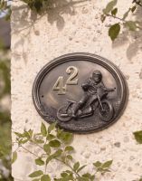 A Number 42 "Speedway" Off Road Motocross House Sign Mounted on a Cream Coloured Cottage Garden Wall - Digital Illustration