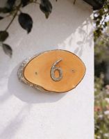 A Number 6 Natural Hard Wood Rustic House Number Sign Mounted on a Cream Coloured Garden Wall - Digital Illustration
