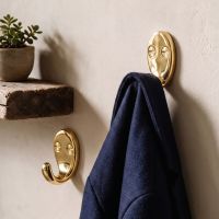 A Pair of Polished Brass Single Pronged Coat Hooks Fitted in a n Entrance Hallway with One Hook Holding a Coat - Digital Illustration 