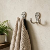 A Pair of Polished Nickel Double Pronged Coat Hook Mounted on a Wall with a Cardigna Hanging From One - Digital Illustration A Pair of Polished Nickel Double Pronged Coat Hook Mounted on a Wall with a Cardigna Hanging From One - Digital Illustration