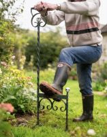 A Racing Green Boot Scraper Pictured Being Used on a Garden Lawn Next to a Flower Border - Digital Illustration A Racing Green Boot Scraper Pictured Being Used on a Garden Lawn Next to a Flower Border - Digital Illustration