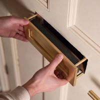 A Satin Brass Traditional Door Letterbox being Mounted onto a White Door - Digital Illustration A Satin Brass Traditional Door Letterbox being Mounted onto a White Door - Digital Illustration