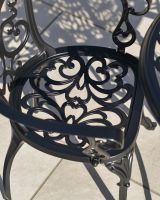 Aged Black "Harlington" Two Seater Garden Table & Chair Set Close Up Ornate Design Aged Black "Harlington" Two Seater Garden Table & Chair Set Close Up Ornate Design