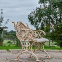 View of the Side of the Aged Cream Cast Iron Dog One Seat Park Bench