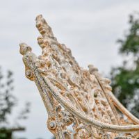 Side view of Aged Cream Cast Iron Bench