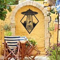 "Get in Loser" Alien Wall Art on a Yellow Brick Wall in the Garden