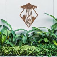 "Get in Loser" Alien Wall Art Above a Bush Outdoors