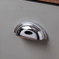 An Art Deco Concealed Cup Drawer Pull in Polished Chrome Fitted on a Light Grey Kitchen Cabinet in a Modern Home - Digital Illustration An Art Deco Concealed Cup Drawer Pull in Polished Chrome Fitted on a Light Grey Kitchen Cabinet in a Modern Home - Digital Illustration