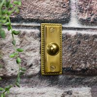 Solid brass door buzzer on brick wall