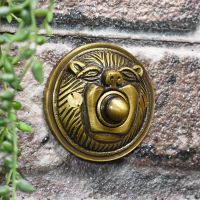 Polished Brass Lion Face bell push on brick wall Polished Brass Lion Face bell push on brick wall