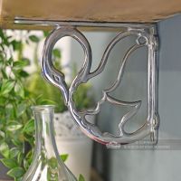 Side view of cast swan pattern on bright chrome living room shelf bracket