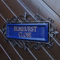 Blue "Belgravia" Ornate Wrought Iron Scrolled Sign on a Wooden Wall Blue "Belgravia" Ornate Wrought Iron Scrolled Sign on a Wooden Wall