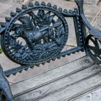 Close up of Aged Black "Dog" Motif on Single Seat Bench Close up of Aged Black "Dog" Motif on Single Seat Bench