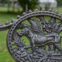 Close up of "Dog" Motif on Single Seater Aged Black Bench Close up of "Dog" Motif on Single Seater Aged Black Bench