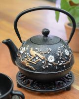 "Mejiro" Cast Iron Japanese Style Teapot - Black & Gold placed on a stand