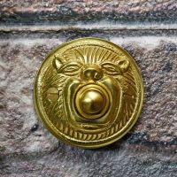 Polished brass bell push on brick wall 