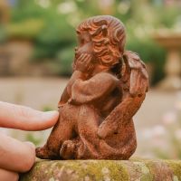Digital illustration of Rustic Cast Iron Winged Adoring Angel Sculpture side view with hand in shot for scale