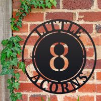 Circular Iron House Name Sign Mounted o a Brick Wall