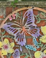 Close up of rustic finish colourful butterfly detail on garden wall art Close up of rustic finish colourful butterfly detail on garden wall art