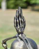 Close up of intricate hand detail on brushed gold skeleton sculpture