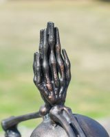 Close up of intricate skeleton hands detail on brushed copper garden statue