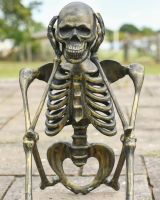 Close up of brushed gold hear no evil skeleton outdoor statue
