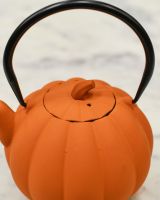 Close up of lid detail on pumpkin orange cast iron teapot Close up of lid detail on pumpkin orange cast iron teapot
