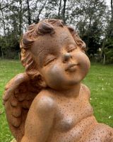 Close up of intricate detail on rustic finish cast iron cherub garden statue