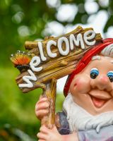 Close up of intricate detail on welcome sign on colourful garden gnome ornament Close up of intricate detail on welcome sign on colourful garden gnome ornament