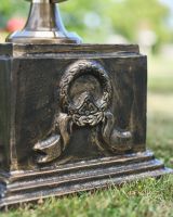 Close up of wreath and ribbon detail on brushed bronze garden column Close up of wreath and ribbon detail on brushed bronze garden column
