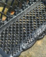 Close up of intricate seat detailing on black garden bench