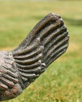 Close up of intricate tail detail on verdigris garden sculpture