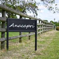 Standing House Name Sign in Situ Next to a Wooden Fence Standing House Name Sign in Situ Next to a Wooden Fence