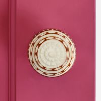 Red and white door knob on pink door Red and white door knob on pink door