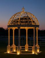 Digital illustration of Deluxe Wrought Iron "Aurelia" French Cream Gazebo lit up with fairy lights at night