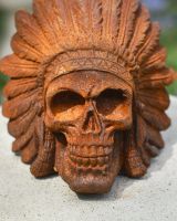 detailed close up of rusted cast iron skull in headdress garden ornament