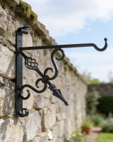 Digital illustration of "Cupid"s Arrow" Blacksmith Iron Hanging Bracket mounted on stone wall