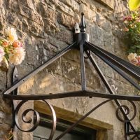 Digital illustration of "Honeysuckle Cottage" Wrought Iron Door Canopy in black close up view of foof and finial Digital illustration of "Honeysuckle Cottage" Wrought Iron Door Canopy in black close up view of foof and finial