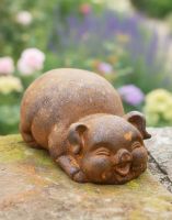 Digital illustration of Rustic Cast Iron "Rounded Lying" Pig Garden Sculpture on a garden wall