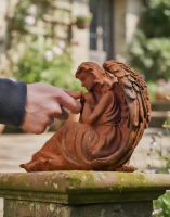 Digital illustration of Rustic Cast Iron Angel in Thought Sculpture with hand in shot for scale Digital illustration of Rustic Cast Iron Angel in Thought Sculpture with hand in shot for scale