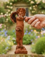 Digital illustration of Rustic Cast Iron Winged Cherub with Butterfly Sculpture with hand in shot for scale